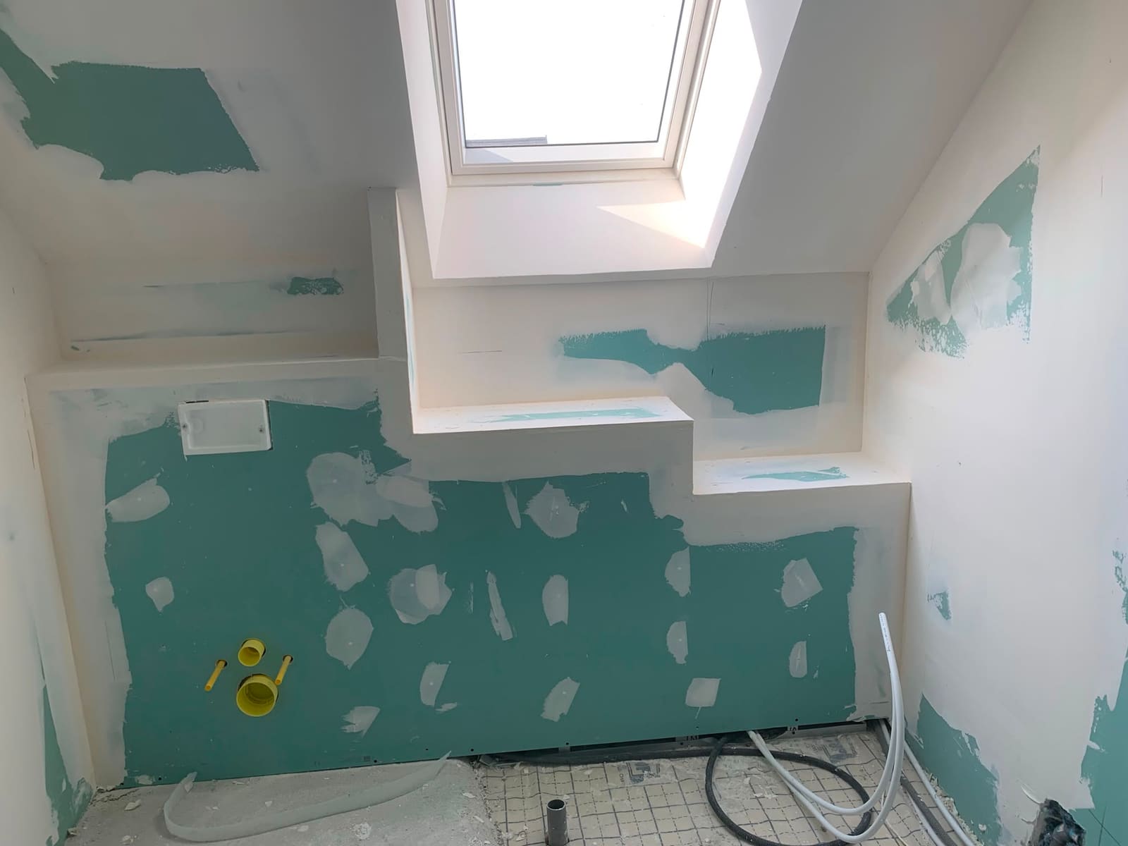 Salle de bain sous combles en cours de finition, plaques de plâtre hydrofuges, caisson et fenêtre de toit
